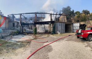 Incendio avvolge una tettoia e raggiunge le case vicine