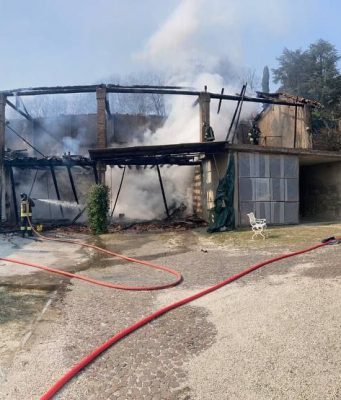 Incendio avvolge una tettoia e raggiunge le case vicine